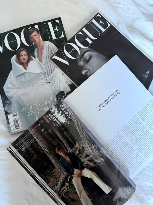 Vogue Scandinavia og Vogue Italia sammen med et åbent magasin på et lyst underlag.