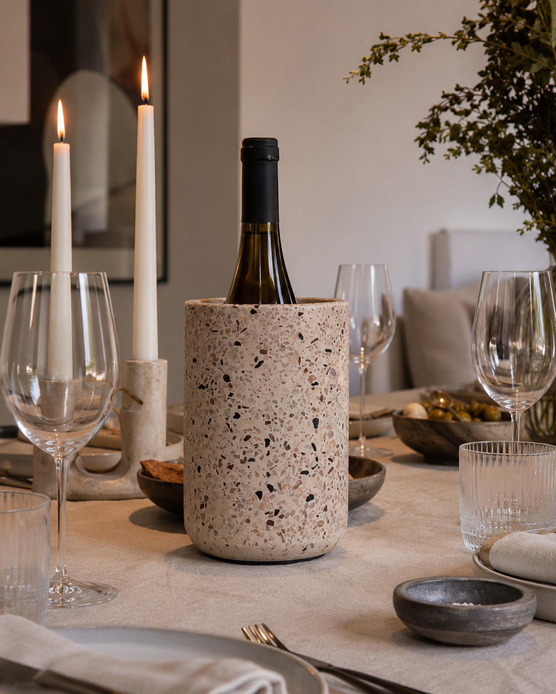 Vinkøler i cement med terrazzo-mønster på dækket middagsbord med vinglas og stearinlys