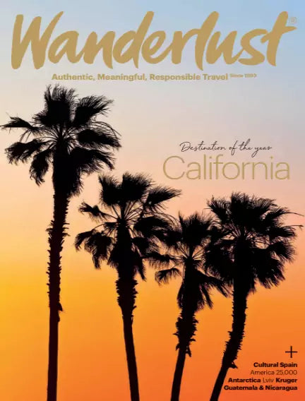 Forside af Wanderlust med palmer i silhuet mod en orange solnedgang. California er fremhævet som “Destination of the Year”.